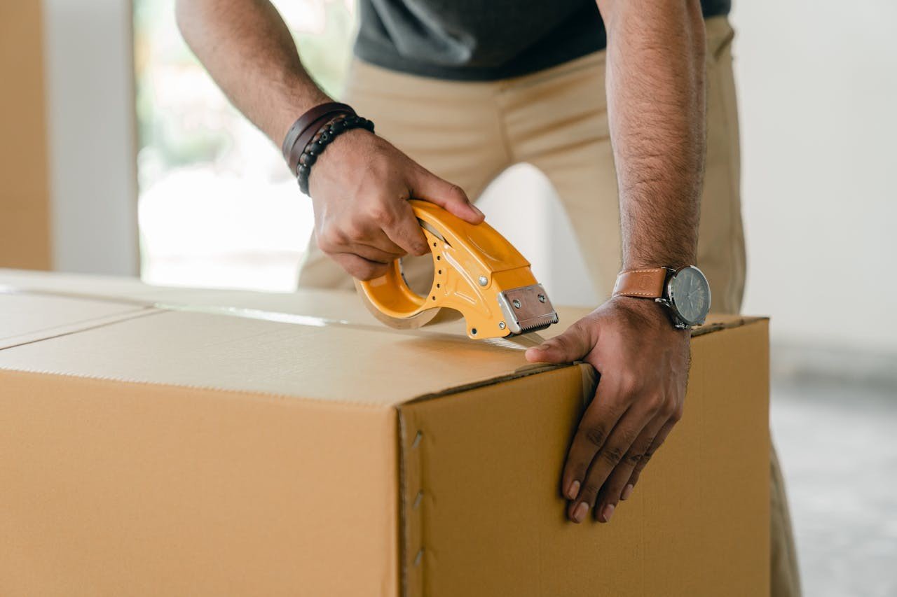 A man taping a carrying box with Scotch tape.